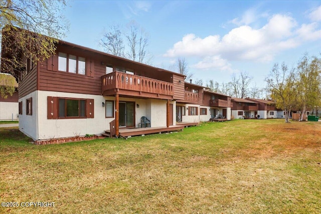rear view of house with stucco siding, a lawn, and a deck