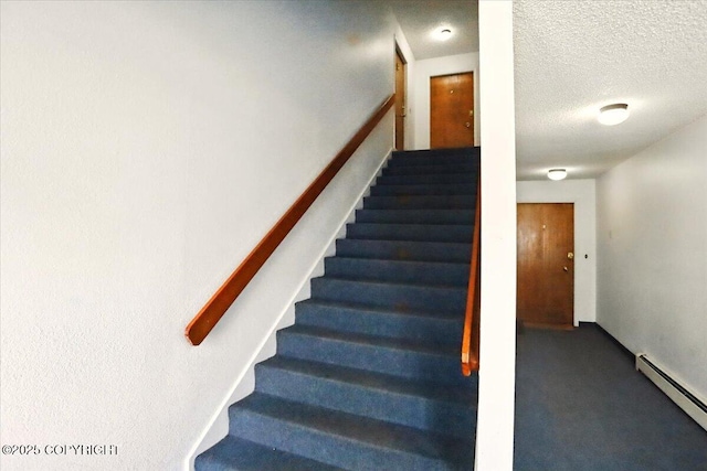 stairway with baseboard heating, carpet, and a textured ceiling
