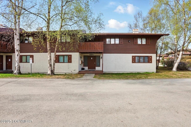 townhome / multi-family property with a chimney and stucco siding