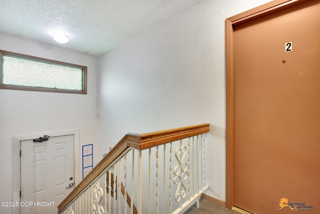 stairs featuring a textured ceiling