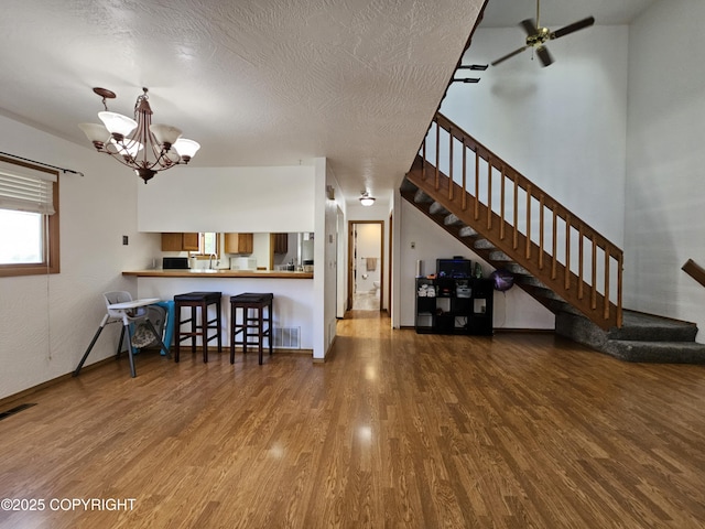 3213 Tayshee Cir, Anchorage, AK 99504 - living area featuring wood finished floors, a chandelier, stairway, and a textured ceiling