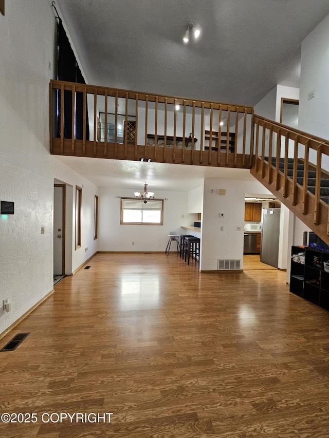 3213 Tayshee Cir, Anchorage, AK 99504 - unfurnished living room with a chandelier, a towering ceiling, wood finished floors, and stairway