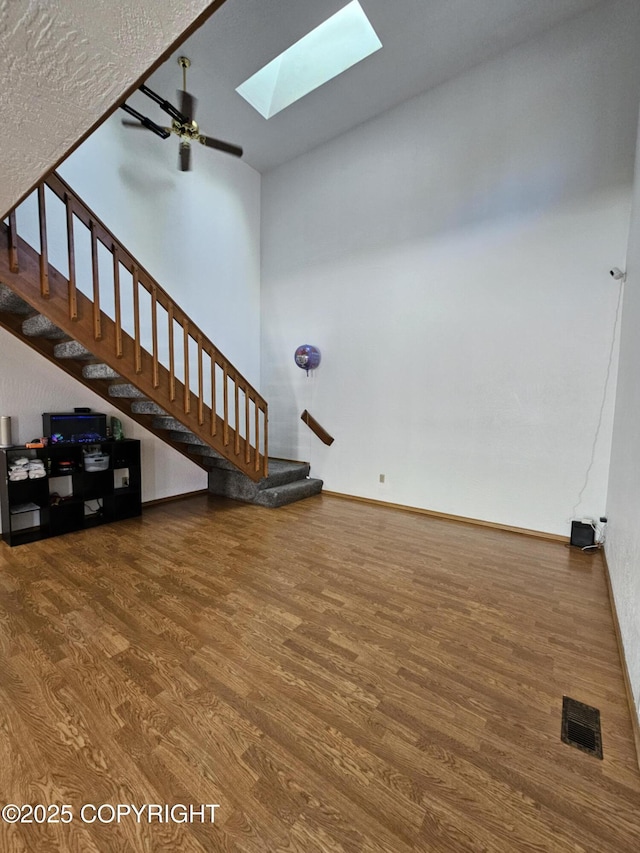 3213 Tayshee Cir, Anchorage, AK 99504 - unfurnished living room with wood finished floors, a skylight, stairway, baseboards, and ceiling fan