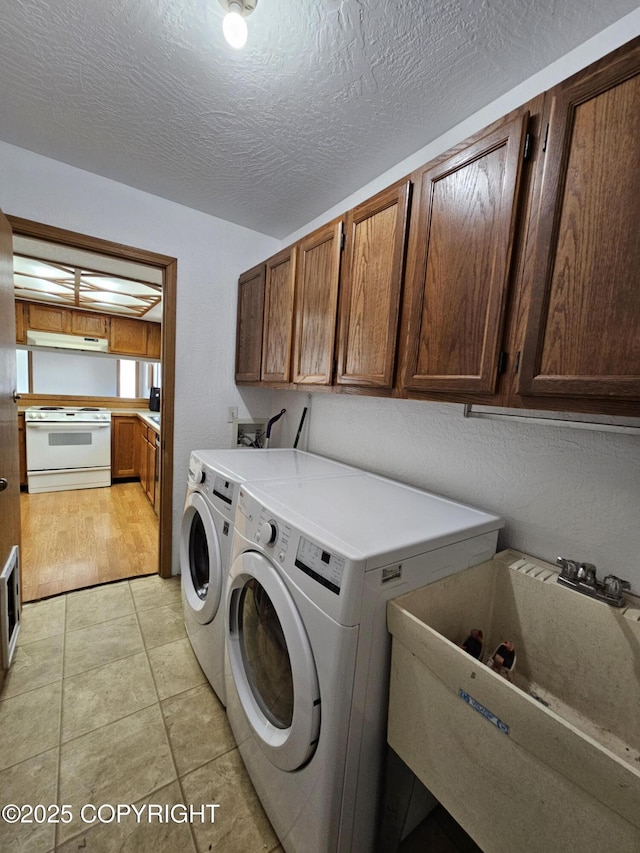 3213 Tayshee Cir, Anchorage, AK 99504 - laundry area with washer and dryer, cabinet space, light tile patterned flooring, and a textured ceiling