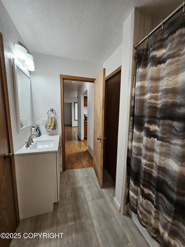 3213 Tayshee Cir, Anchorage, AK 99504 - bathroom with wood finished floors, vanity, curtained shower, and a textured ceiling