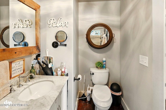 bathroom featuring baseboards, toilet, and vanity