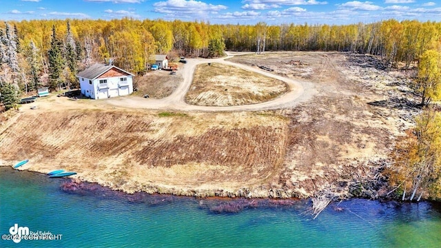 aerial view of property and surrounding area with a heavily wooded area and a large body of water