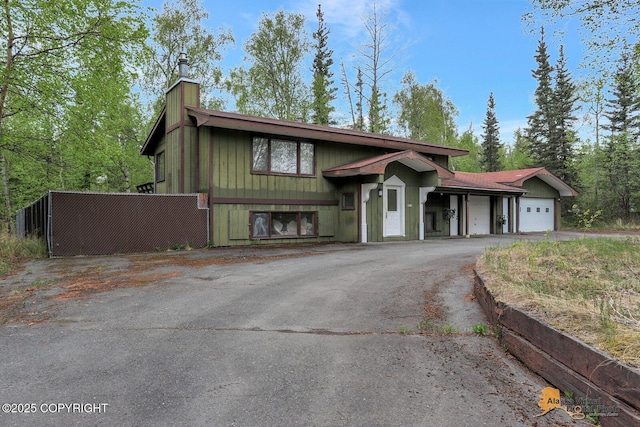 view of front of property with an attached garage, a chimney, and asphalt driveway