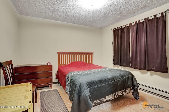 bedroom with a textured ceiling, a baseboard heating unit, and wood finished floors