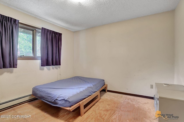 bedroom featuring a baseboard heating unit, a textured ceiling, and baseboards