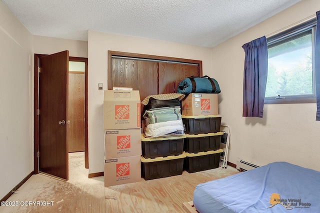 bedroom featuring a baseboard radiator, baseboards, and a textured ceiling