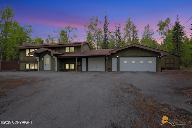 view of front of property with a garage, driveway, and a shed