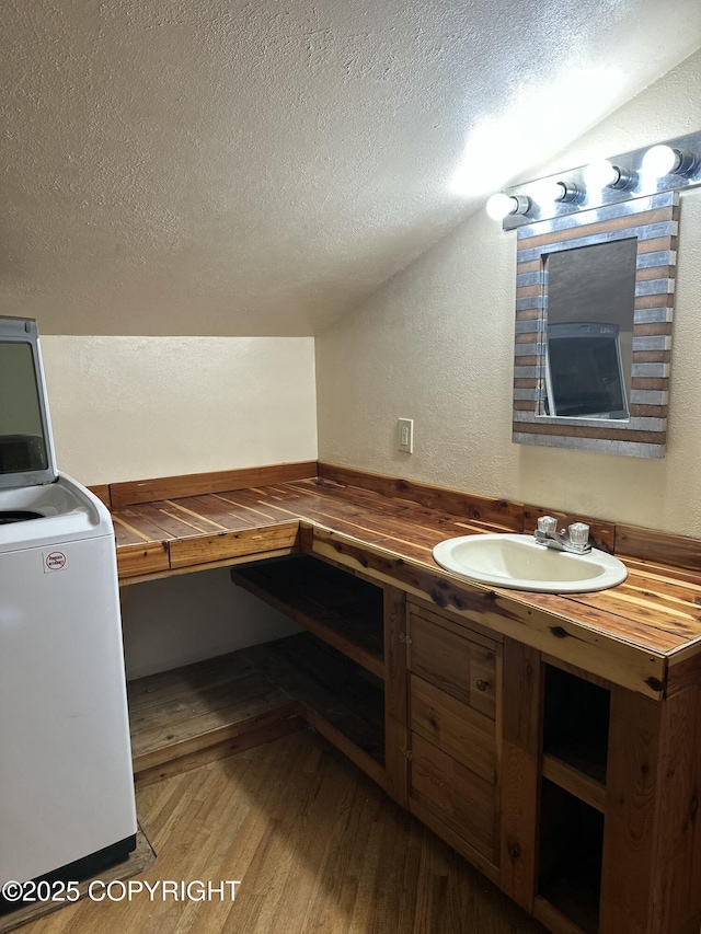 34540 Alamar, Anchor Point, AK 99556 - bathroom featuring wood finished floors, washer / clothes dryer, a textured ceiling, vaulted ceiling, and a textured wall