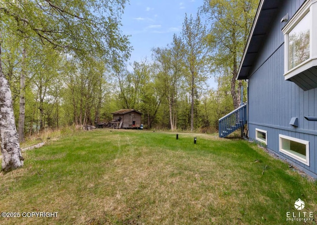 view of grassy yard with stairs and an outbuilding