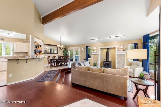 living area with a wood stove, dark wood-style flooring, a chandelier, and baseboards