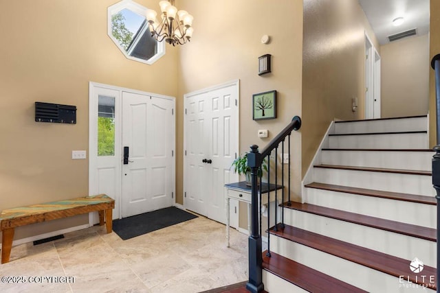 entrance foyer featuring stairs, a chandelier, a high ceiling, and baseboards