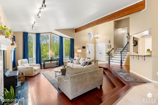 living room with stairs, beamed ceiling, rail lighting, baseboards, and high vaulted ceiling