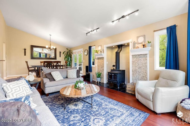 living area featuring wood finished floors, healthy amount of natural light, rail lighting, a chandelier, and vaulted ceiling