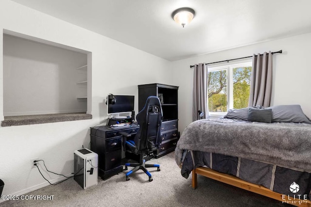carpeted bedroom featuring an office area and baseboards