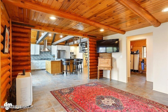 kitchen featuring freestanding refrigerator, wall chimney range hood, beamed ceiling, wood ceiling, and rustic walls