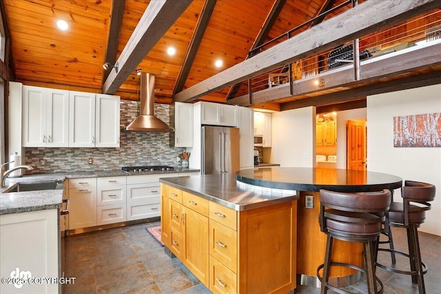 kitchen featuring a sink, wooden ceiling, stainless steel appliances, wall chimney range hood, and stainless steel counters