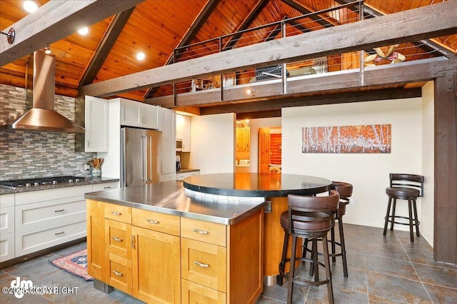 kitchen with stainless steel counters, stainless steel appliances, wood ceiling, a kitchen island, and beamed ceiling