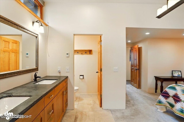 bathroom featuring toilet, recessed lighting, double vanity, and a high ceiling