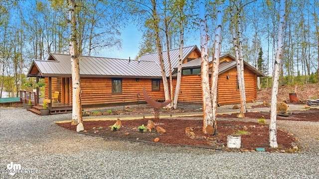 log cabin featuring log exterior, a standing seam roof, metal roof, and a porch