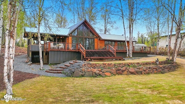 rear view of property featuring a wooden deck, a lawn, log siding, and metal roof