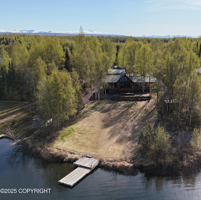 view of subject property featuring a forest and a nearby body of water