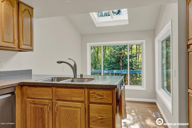 19426 Pribilof Loop, Eagle River, AK 99577 - kitchen with a sink, stainless steel dishwasher, a skylight, a peninsula, and light wood finished floors