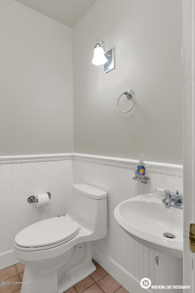 19426 Pribilof Loop, Eagle River, AK 99577 - bathroom featuring tile patterned floors, toilet, a wainscoted wall, and a sink