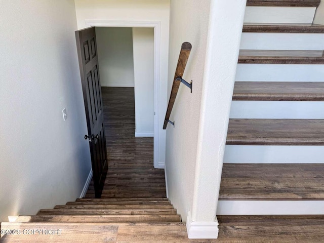 staircase featuring wood finished floors and baseboards
