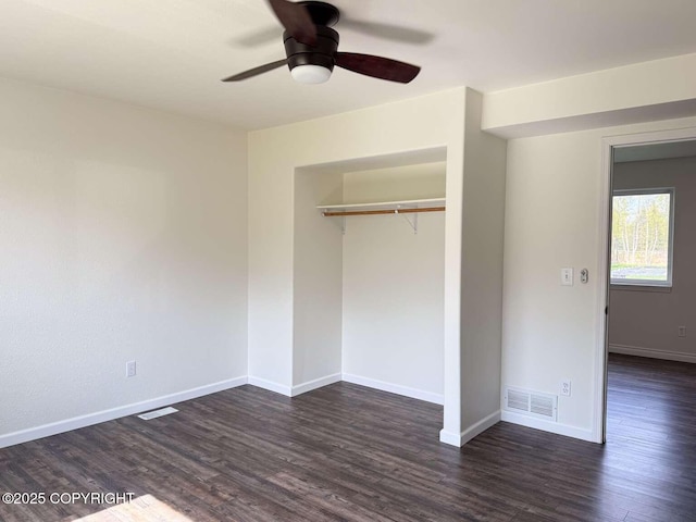 unfurnished bedroom featuring dark wood finished floors, a closet, baseboards, and ceiling fan