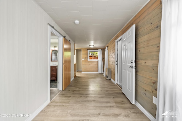 4207 Cope St, Anchorage, AK 99503 - hallway featuring wood walls, a barn door, light wood-style flooring, and baseboards