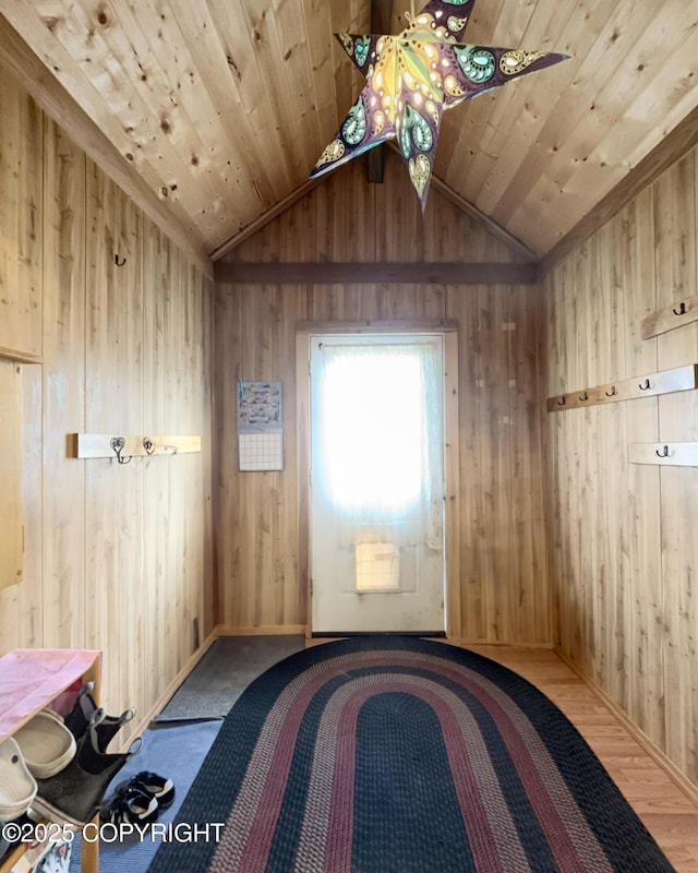 interior space with wooden walls, vaulted ceiling, wood finished floors, and baseboards