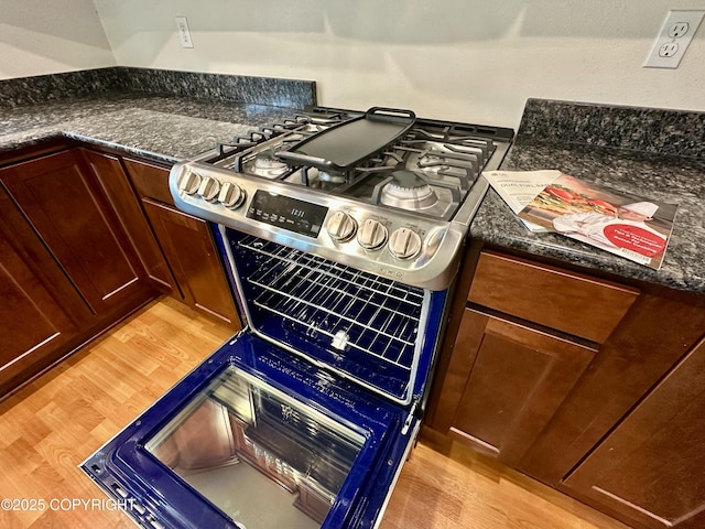 5612 Grand Teton Loop, Anchorage, AK 99502 - kitchen view of stainless steel range with gas stovetop, light wood finished floors, and dark stone counters