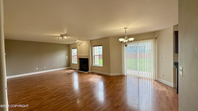 5612 Grand Teton Loop, Anchorage, AK 99502 - unfurnished living room with a glass covered fireplace, a chandelier, wood finished floors, and baseboards