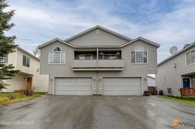 view of front of house with an attached garage, asphalt driveway, and a balcony