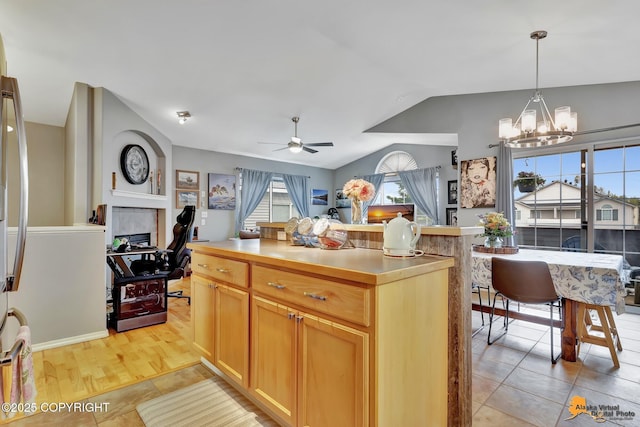 kitchen with light tile patterned floors, vaulted ceiling, ceiling fan, a chandelier, and decorative light fixtures