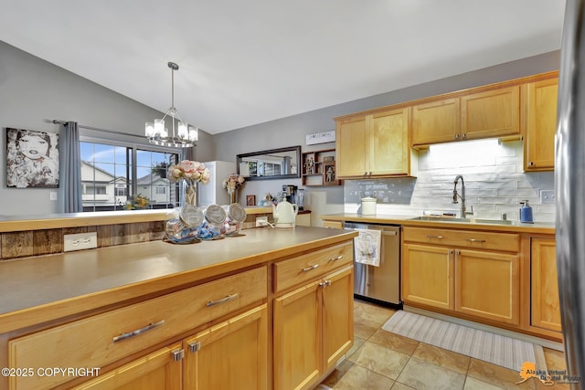 kitchen with appliances with stainless steel finishes, a sink, vaulted ceiling, backsplash, and a chandelier