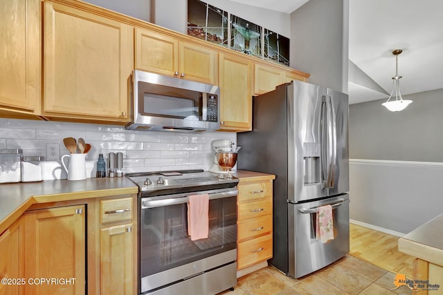 kitchen with stainless steel appliances, decorative backsplash, light brown cabinetry, and baseboards