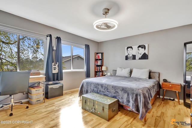 bedroom with wood finished floors, multiple windows, baseboards, and an office area
