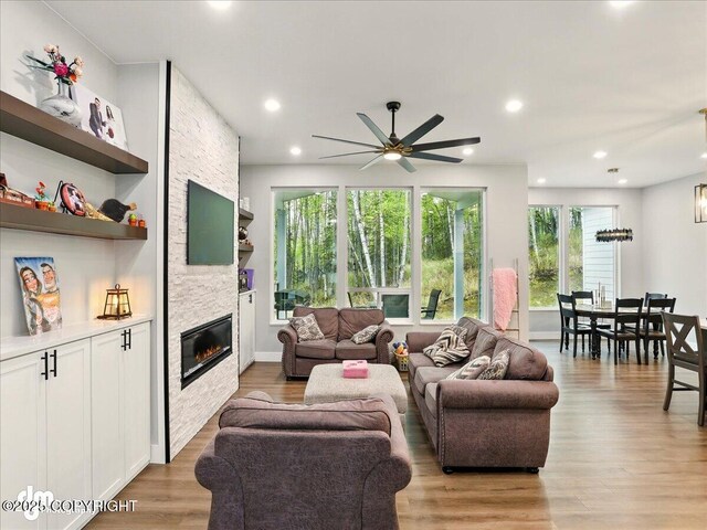 living area featuring a ceiling fan, a fireplace, light wood-style flooring, built in shelves, and recessed lighting