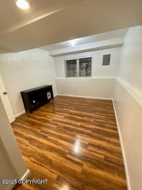 finished below grade area featuring wood finished floors, baseboards, and electric panel
