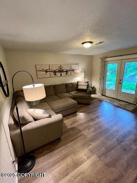 living room with wood finished floors, french doors, and a textured ceiling