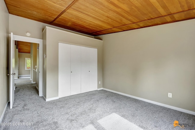 unfurnished bedroom with wood ceiling, carpet flooring, a closet, baseboard heating, and baseboards