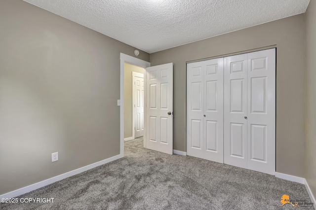 unfurnished bedroom with carpet, a textured ceiling, baseboards, and a closet