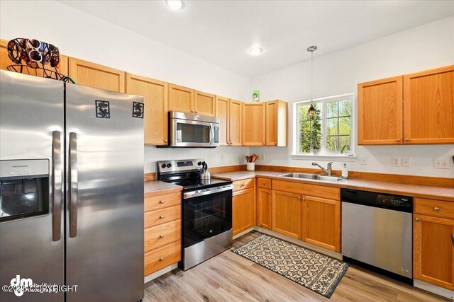 6744 Bogle Bluff Dr, Wasilla, AK 99623 - kitchen with appliances with stainless steel finishes, a sink, light wood-style floors, light countertops, and decorative light fixtures