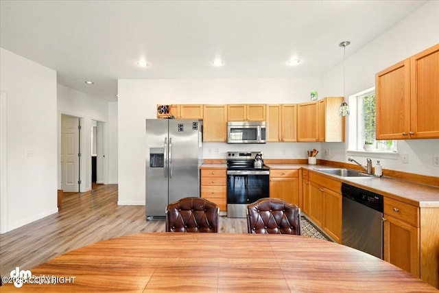 6744 Bogle Bluff Dr, Wasilla, AK 99623 - kitchen featuring stainless steel appliances, a sink, light wood-style floors, hanging light fixtures, and light countertops